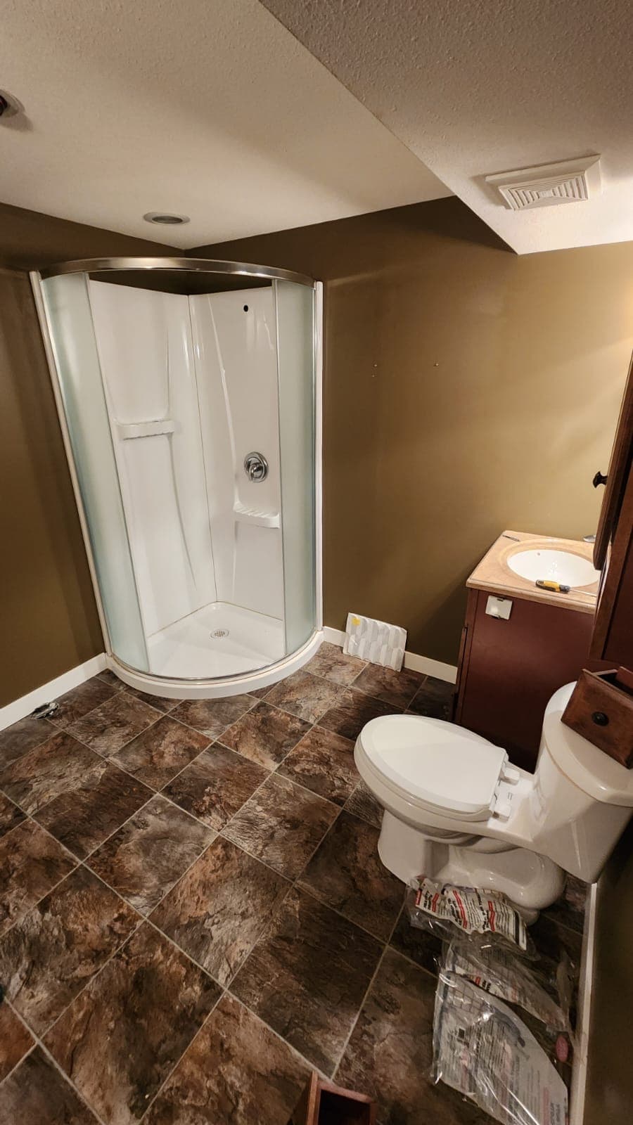 Dark basement bathroom with brown walls and dated tile before renovation, Calgary