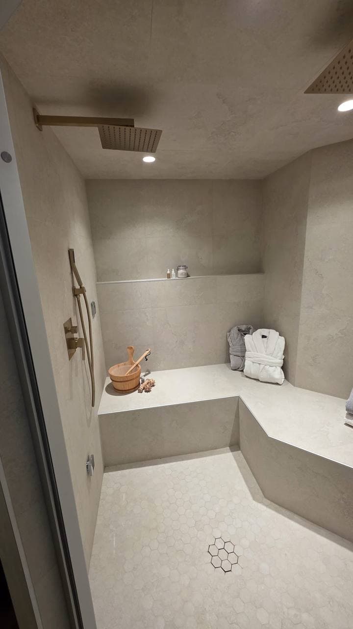 Modern stone steam shower with brushed-gold fixtures and hexagon floor, Calgary